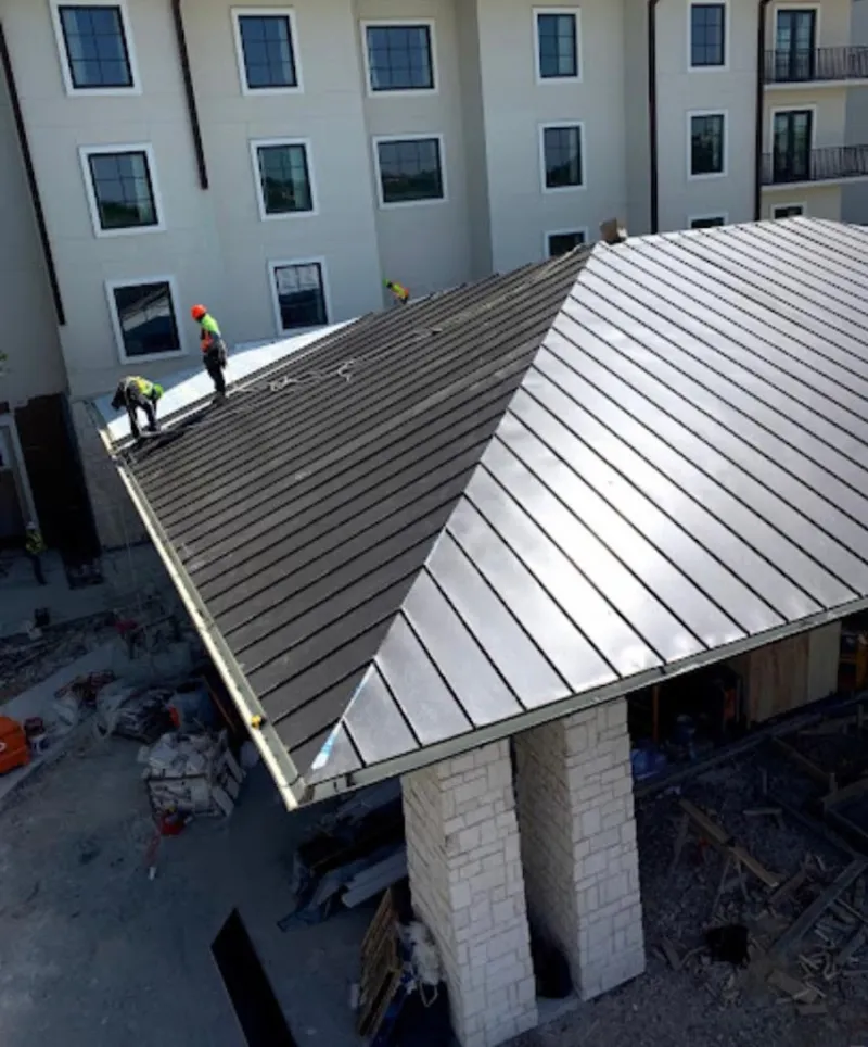 Crew installing standing seam metal roof panels on a commercial project in Columbus